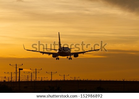 Silhouette of commercial jet landing at LAX during a dramatic sunset.