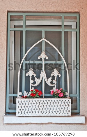 window with bars in the country house and a decorative box with flowers