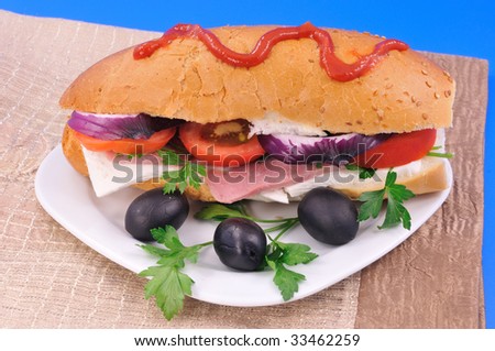 Sandwich with bacon and cheese and black olives on a white plate