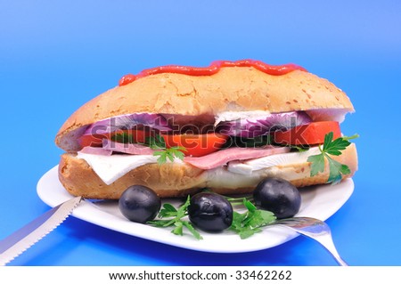 Sandwich with bacon and cheese and black olives on a white plate