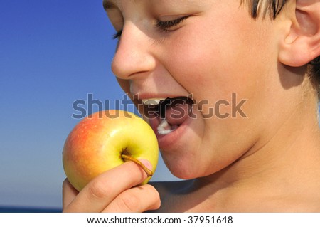 The boy holds in his hand an apple, which wants to bite