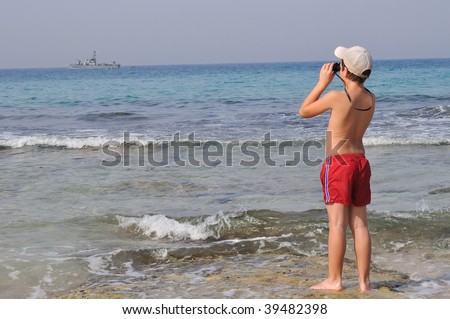 The boy observes in the field-glass of the military ship