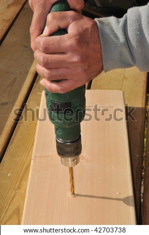 drilling holes in the boards for cladding wooden house