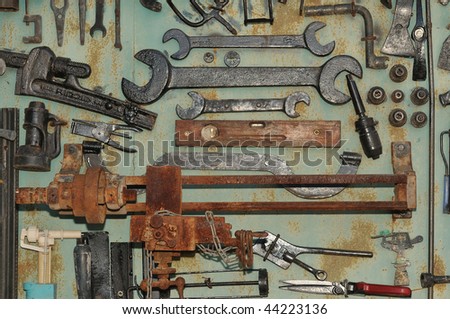 Old tools, wrenches, scissors and a rusty machine on the wall of the garage