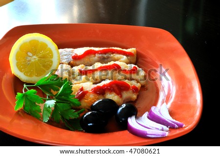 Roasted fillet of bass with olives, lemon and onion in a terracotta dish