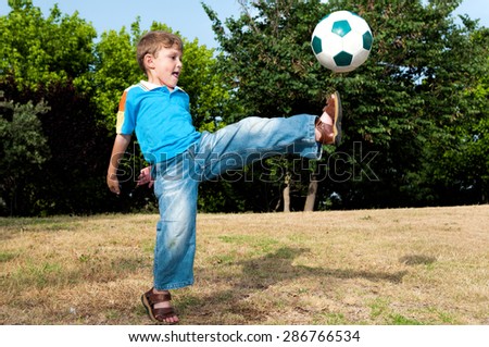 Little football player playing in the park with his father in football and hits the ball with all his strength