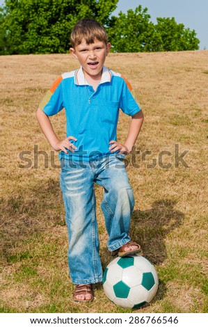 Little football player  has come to play football with his father in the park  and want to have to start the game
