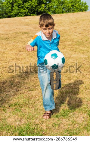 Little football player playing in the park with his father in football and hits the ball with all his strength