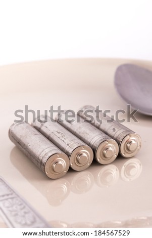 the isolated of old AA battery in food dish is energy consumption concept