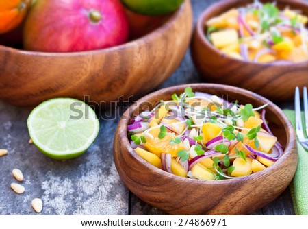 vegetarian salad with mango oranges and red onion on the wooden plate