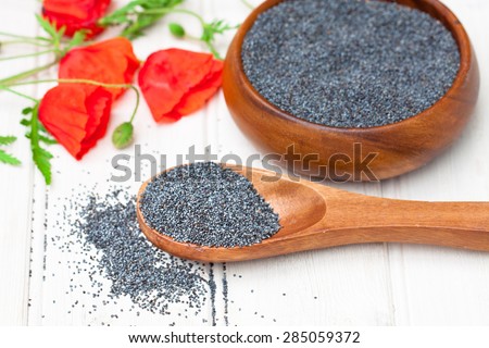 poppy seeds in a wooden bowl on a table with spoon