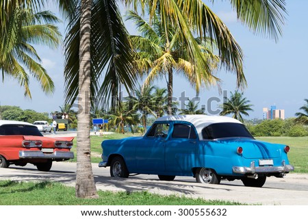 HAVANA, CUBA - JUNE 17, 2015: American red and blue Oldtimer parked under blue sky and palms
