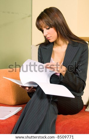 Young woman sitting on chair and reading document