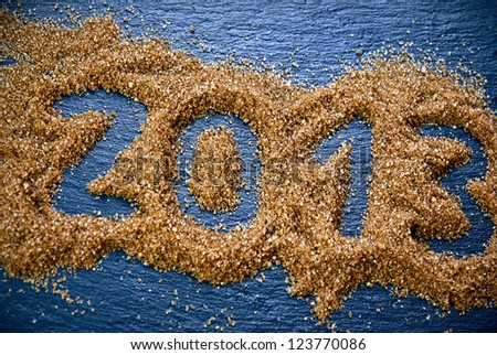 On a blue slate the number 2013 is drawn in a lot of brown sugar./Sweet 2013.