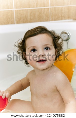 Baby bathing in the bath Smiling baby taking a bath in front of a bouncy ball./Smiling baby taking a bath.