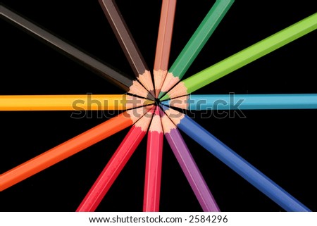 A group of coloured pencils arranged in a star pattern on a back background.