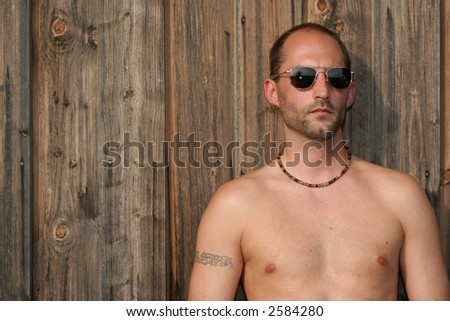 Balding man with sunglasses against a rustical wood background with room for text