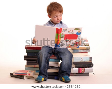 stock photo : Young boy sitting on a pile of books reading against a white 