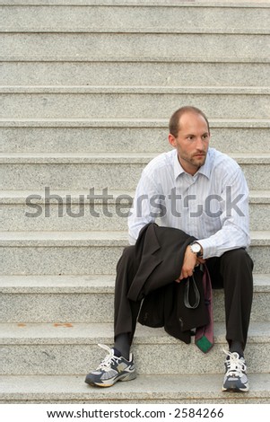 Business man sitting relaxed on stairs with jacket in the hands