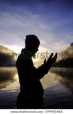 Silhouette of man praying during sunrise at Ranu Kumbolo Lake