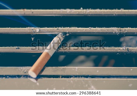 Cigarette burn on dirty metal ashtray at smoking area
