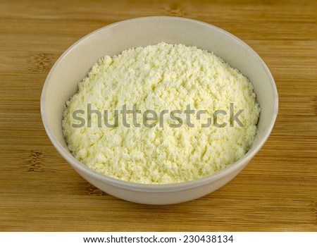 Bowl full of white milk powder against a wooden background