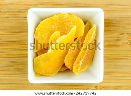 Dehydrated dried mango in white bowl on wooden background