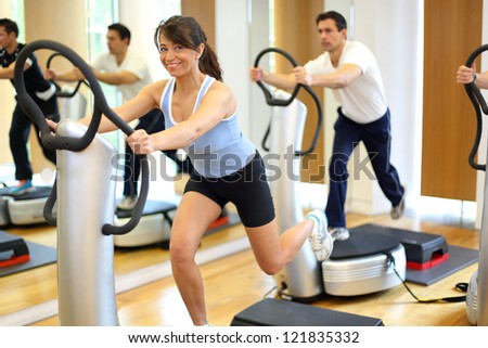 Group of two men and one woman on a vibration massage plate in a gym