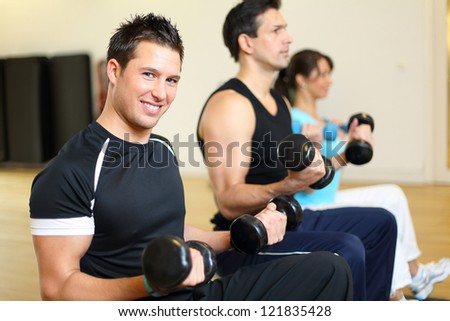 Two men and one woman exercising with dumbbells on gymnastics balls