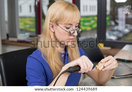 Dental technician with surgical loupes polishing gold tooth in a laboratory