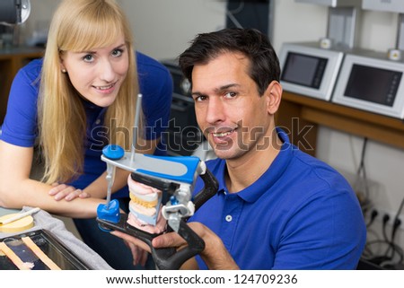 Two dental technicians looking at articulator in a dental lab