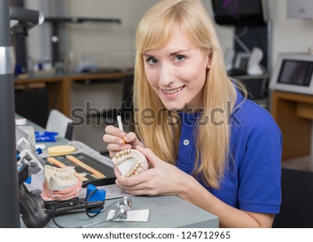 Dental lab technician applying porcelain to dentition mold in a lab