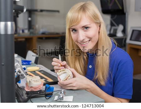 Dental lab technician applying porcelain to dentition mold in a lab