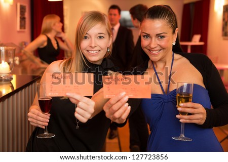 Two beautiful women presenting tickets for a theatre, cinema or a concert