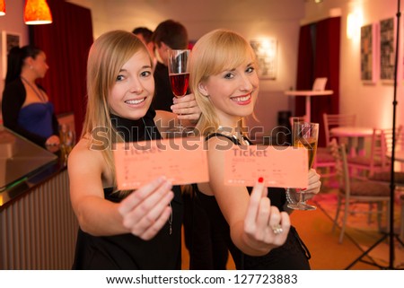 Two beautiful women presenting tickets for a theater, cinema or a concert