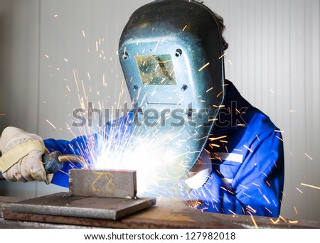Man with welding helmet welding steel