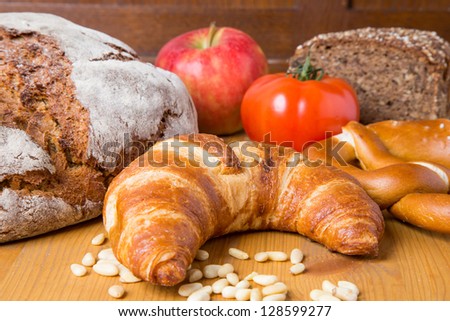 Different types of food such as bread, a tomato, apple, pine seeds and a pretzel