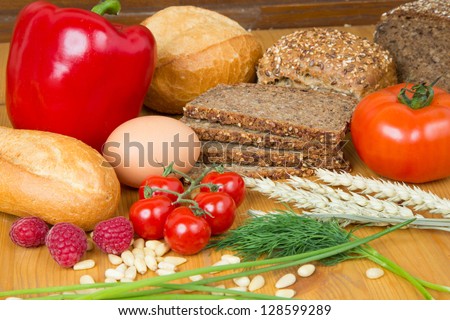 Different types of food such as bread, a tomato, apple, pine seeds, raspberry and a pretzel