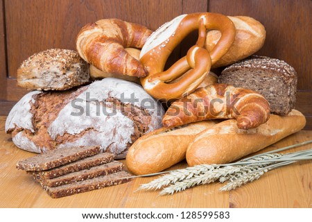 Different types of bakery products such a a loaf of bread, pretzel, whole grain bread and buns
