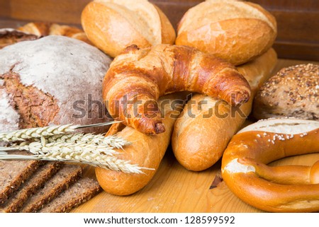 Different types of bakery products such a a loaf of bread, pretzel, whole grain bread and buns