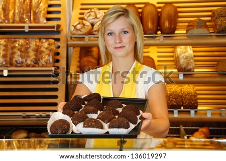 Saleswoman in bakery or confectionery present a tablet of rum balls