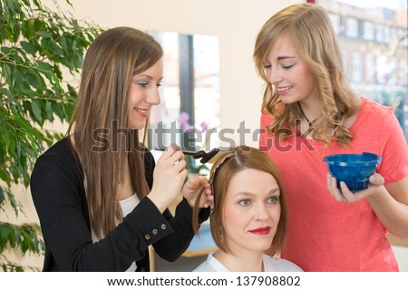hairstylists or hairdresser dying hair of customer with color paint