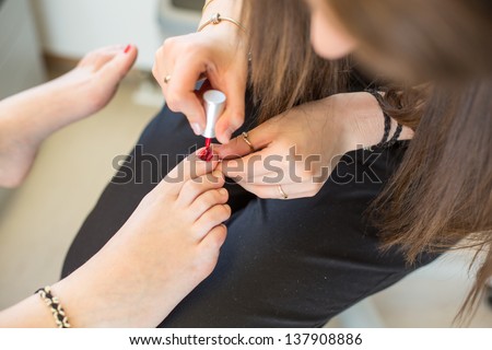 Pedicure applying nail polish to customers toe nails