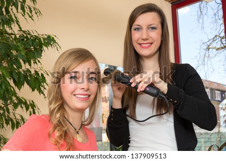Hairdresser in salon making locks for a customer with a hair straightener