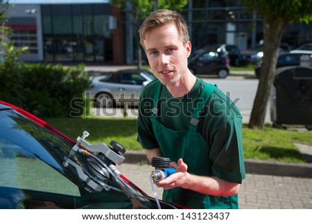 Glazier repairing windshield on a car after stone-chipping damage