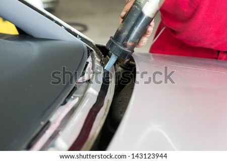 Glazier applying adhesive to install new windshield or windscreen