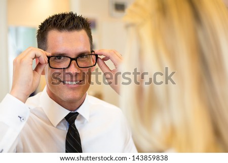 Optician or optometrist consulting a customer about eyeglasses, spectacles and frames in a shop