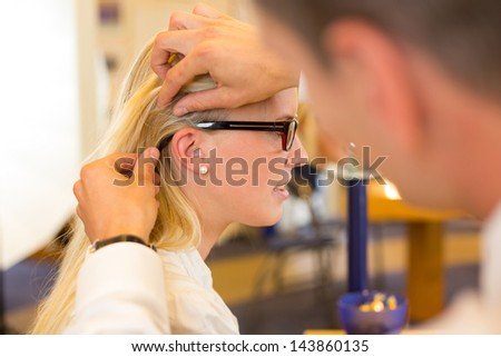 Optician examining correct fit of eyeglass frame for customer in optometrist\'s shop