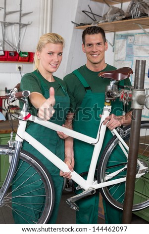 Bicycle mechanic and apprentice repairing a bike in workshop