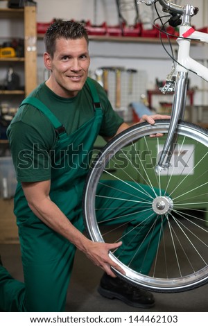 Bicycle mechanic repairing tyre or wheel on bike in a workshop